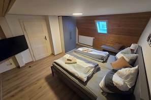 Ein Schlafzimmer mit zwei Betten, einem Fernseher, einem Fenster und einer Holzbalkendecke.