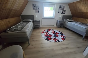 Una habitación con dos camas individuales, un radiador, una ventana y una alfombra redonda.
