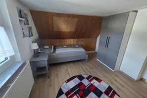 Une chambre à coucher avec un lit, une table de chevet, une lampe, une armoire et un radiateur.