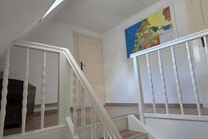 Una escalera con barandilla blanca que lleva a una plataforma, un radiador y un mapa en la pared.