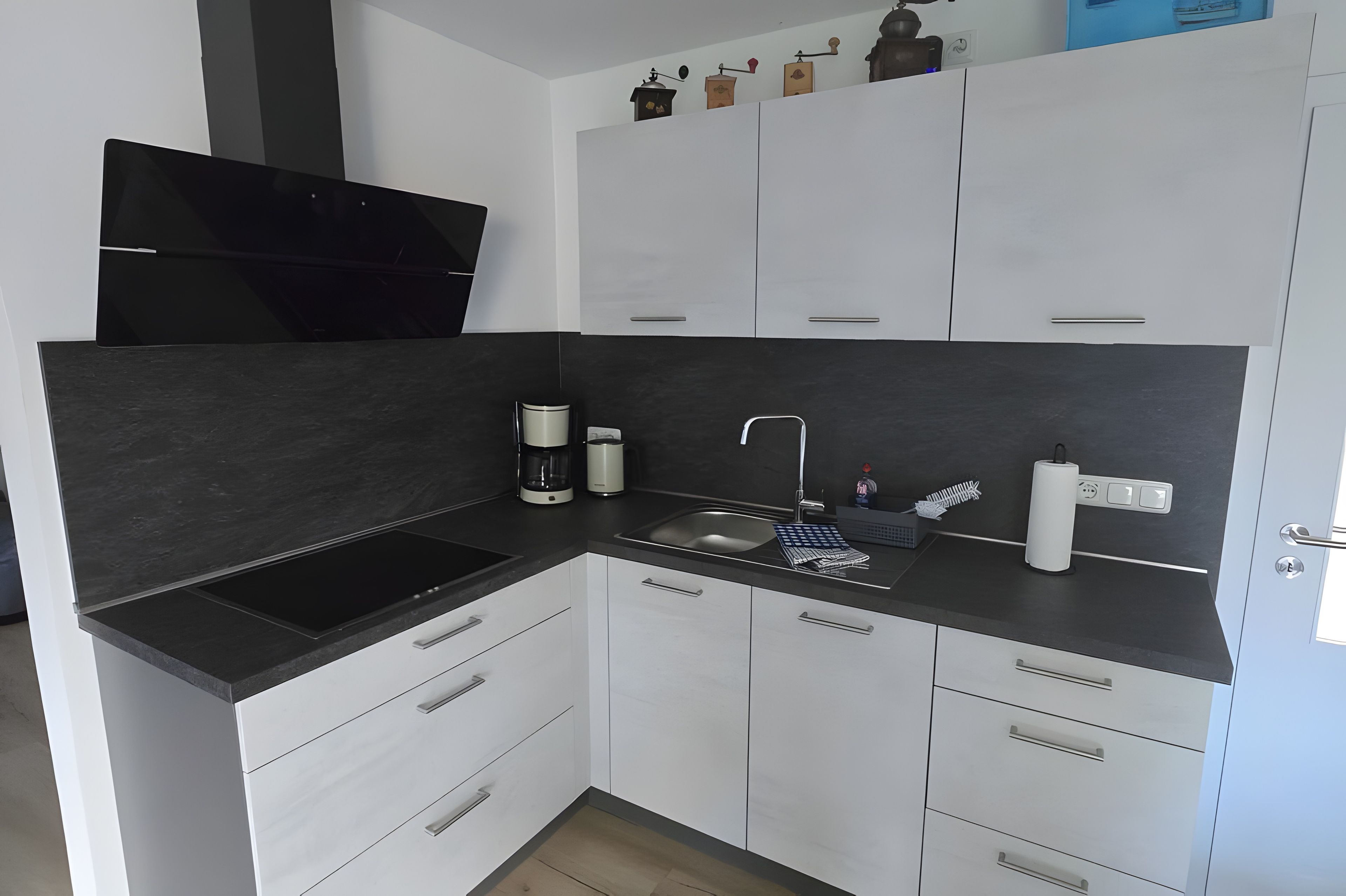 Eine moderne Küche mit schwarzem Arbeitsplatz, weißen Schränken, einem Einbauofen und einer Spüle.
