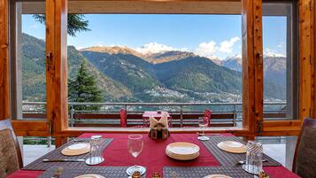 A dining table set for four with a mountain view through large windows.
