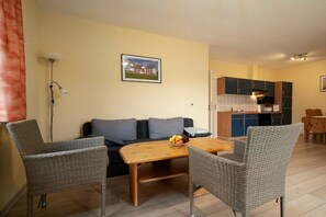 A living room with a sofa, two wicker chairs, a wooden coffee table, and a small fruit bowl. - Holiday apartment Haus Vietzen 1 (Rechlin)