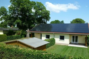 Een huis met een zonnepaneel dak, een klein terras en een verzorgd gazon.