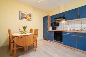 A kitchen with blue cabinets, a wooden dining table, and a fruit bowl. - Holiday apartment Haus Vietzen 2 (Rechlin)