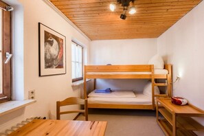 A bunk bed room with a wooden ceiling, a framed picture on the wall, and a table with a chair. - Holiday apartment with 1 bedroom (Füssen-Hopfen am See)
