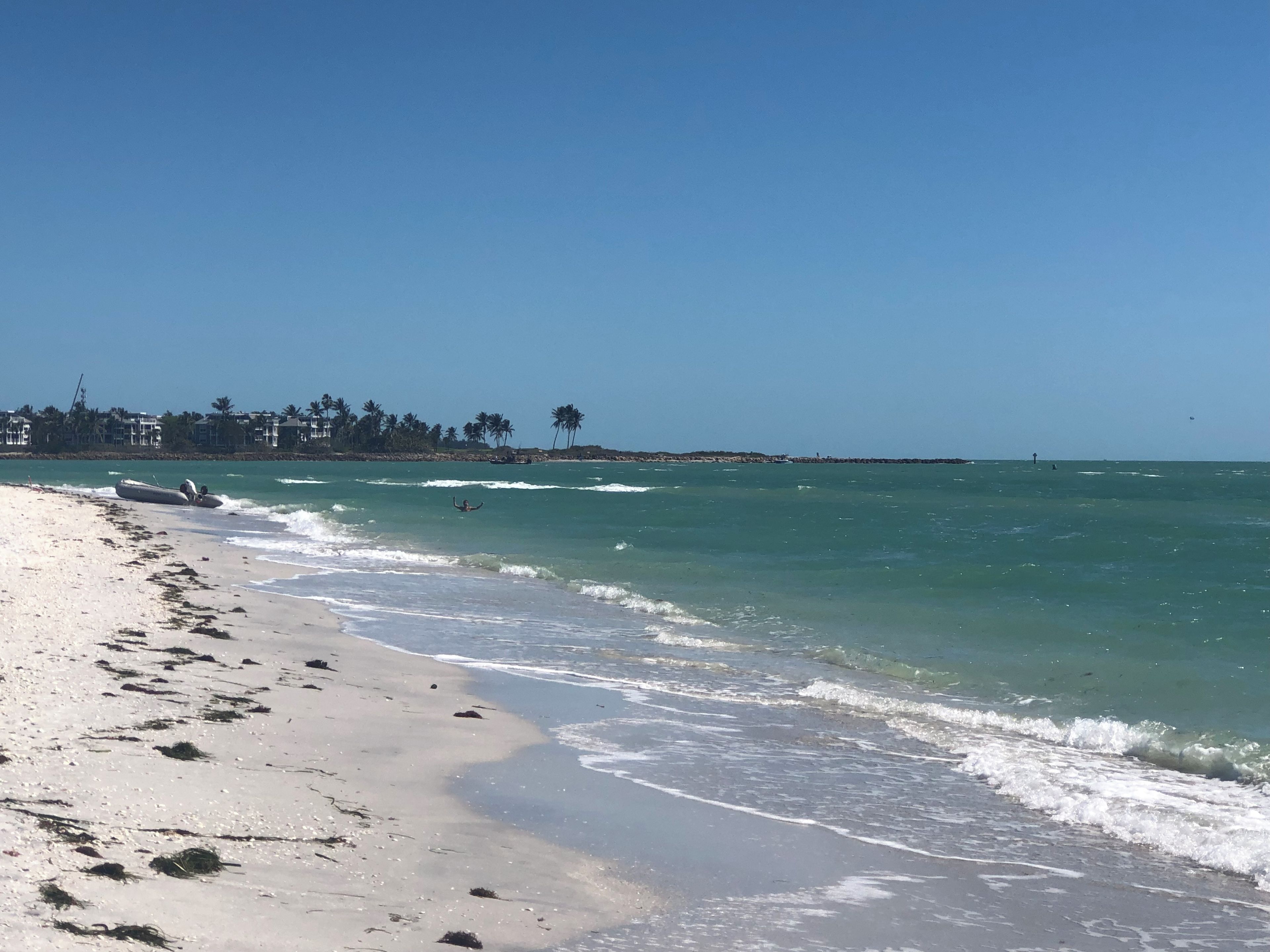 Una playa con cielo despejado, orilla arenosa y mar tranquilo.