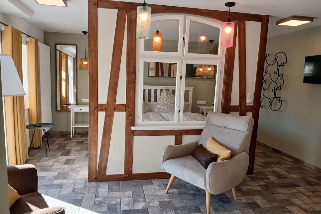 A room with a large window, a chair, a table, and a mirror.