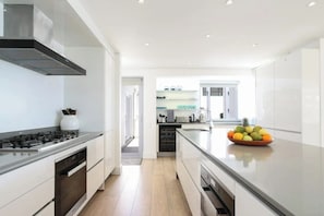 Een moderne keuken met een centraal eiland, inbouwapparatuur en uitzicht op de aangrenzende eetruimte.