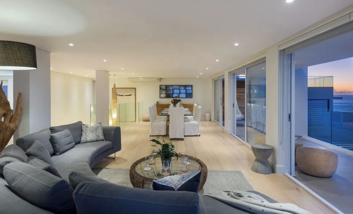 A modern living room with a sofa, coffee table, and a dining area with chairs.