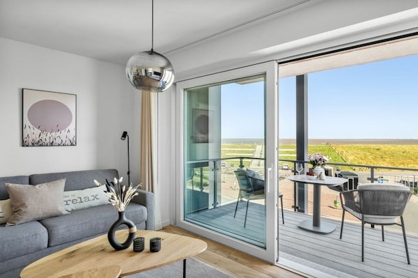 Ein stilvolles Wohnzimmer mit einer Couch, einem Couchtisch und Blick ins Freie.