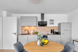 Une cuisine moderne avec une table ronde en bois, des meubles de couleur grise et une hotte noire.