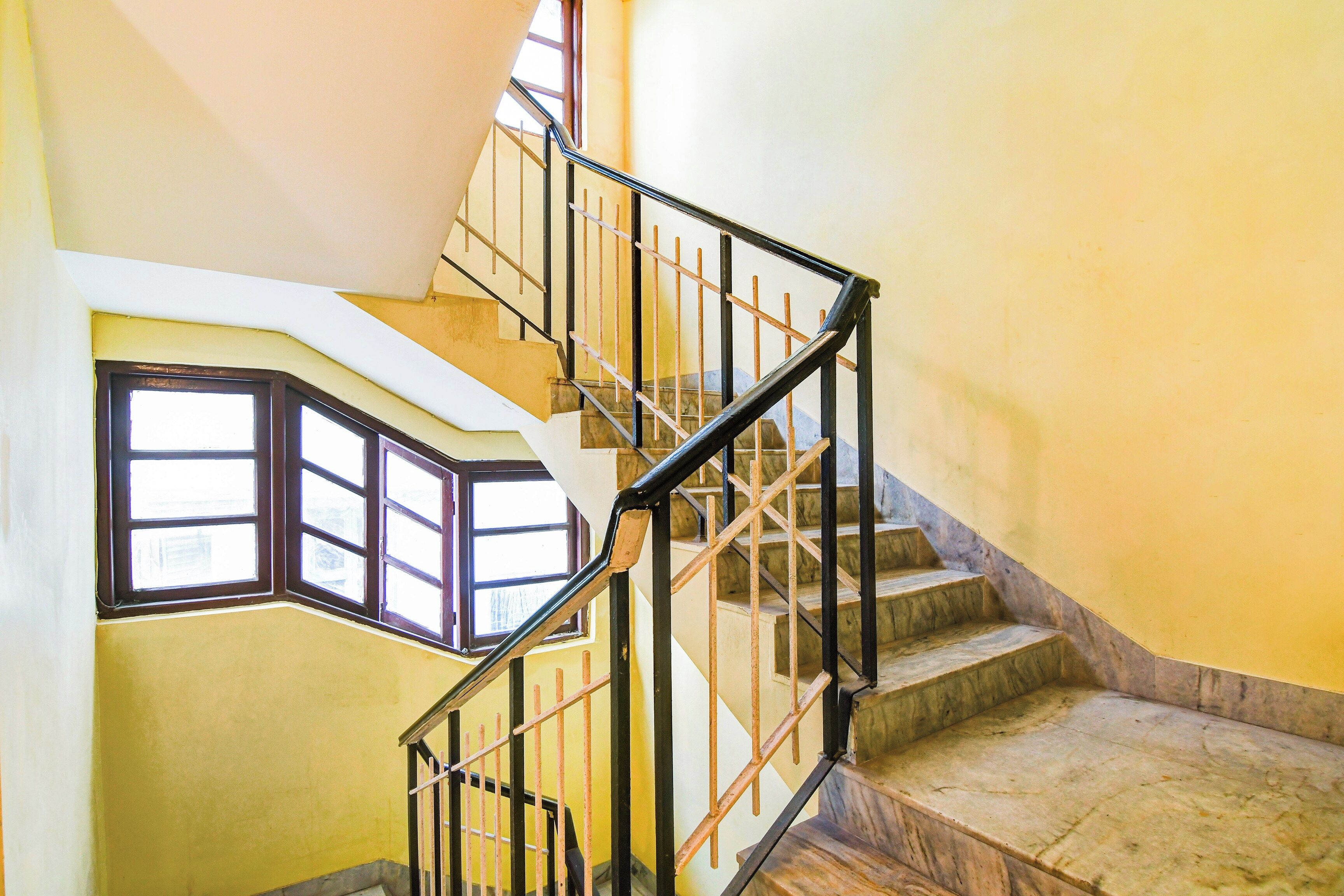 Una escalera con barandilla, escalones de madera y un ventanal en el rellano.
