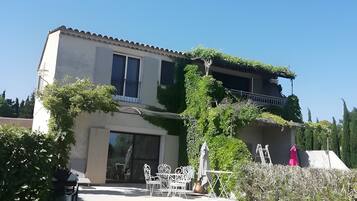 A two-story house with a patio area, outdoor furniture, and a ladder.