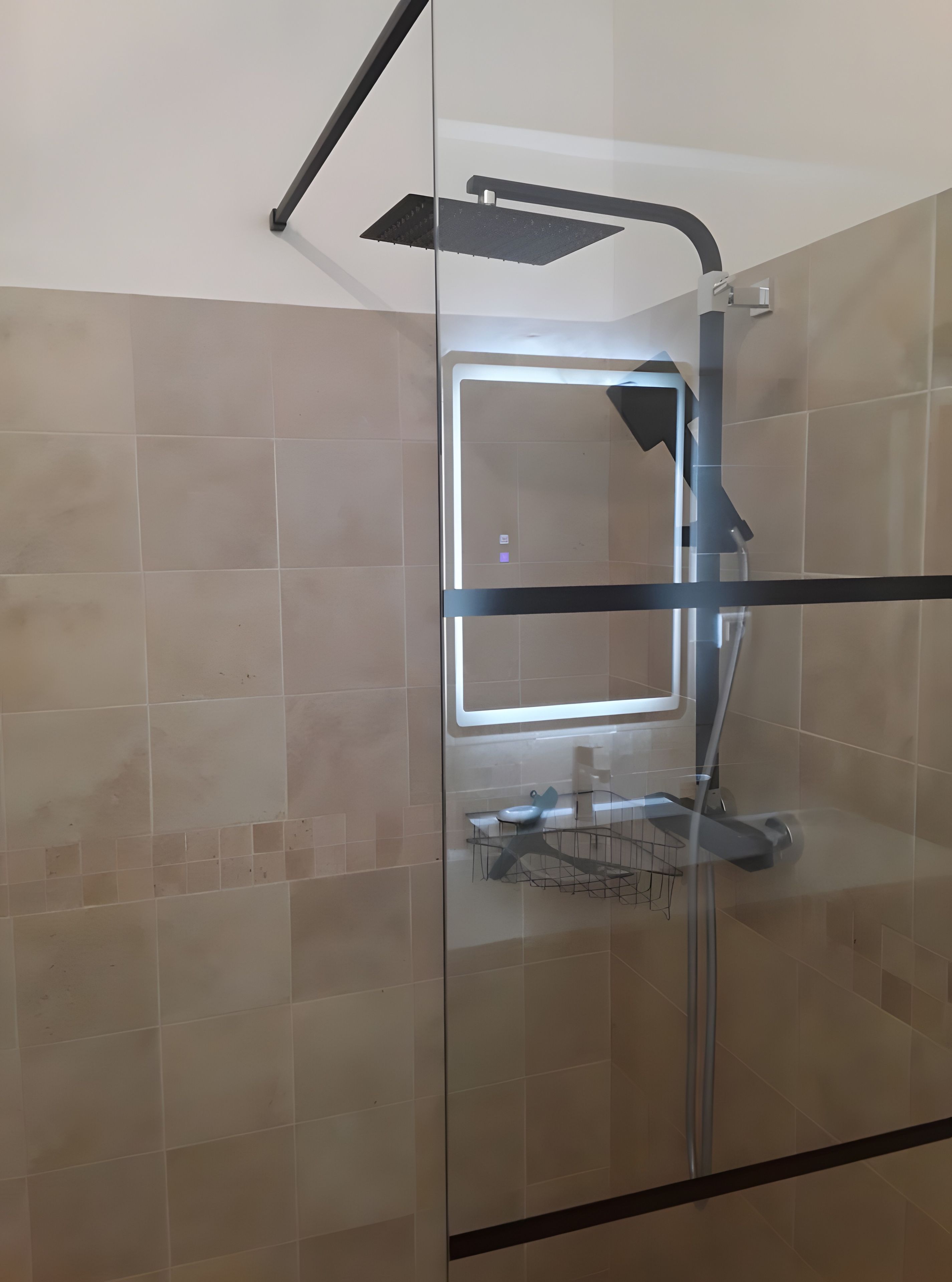Une cabine de douche moderne dotée d’une porte en verre, d’un pommeau de douche à main et d’un porte-serviettes.