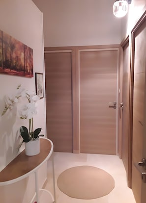 Un couloir avec un espace salon circulaire, une plante en pot, un tableau et deux portes.