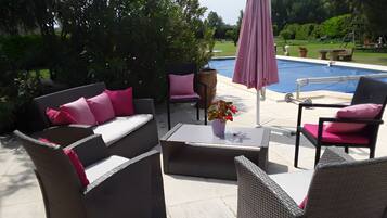 An outdoor patio with wicker furniture, a coffee table, and a pink umbrella.