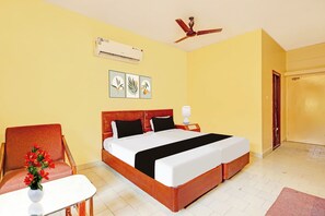 A hotel room with a bed, a chair, a small table, an air conditioner, and a ceiling fan. - Hotel O Gajuwaka Near kurmanpalem (Visakhapatnam)