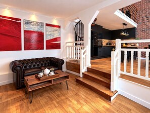 Un salon moderne avec un canapé en cuir, une table basse en bois et une œuvre d’art abstraite accrochée au mur.