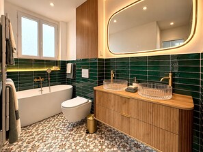 Une salle de bain moderne avec une baignoire sur pieds, des toilettes et un meuble-lavabo avec un miroir.