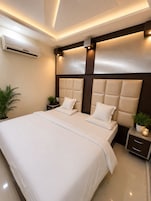 Quarto moderno com uma cama grande, mesas de cabeceira e ar condicionado.