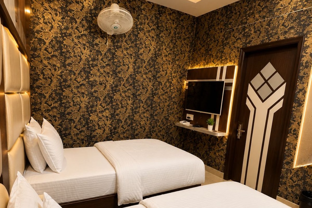 Habitación de hotel con dos camas, un espejo grande, un ventilador de techo y una puerta con diseño geométrico.