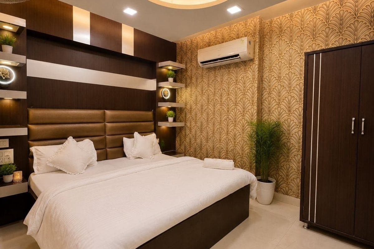 Un dormitorio moderno con una cama grande, estanterías empotradas, un equipo de aire acondicionado y una lámpara de techo decorativa.
