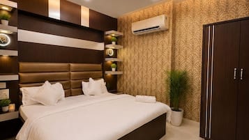 Et moderne soveværelse med en stor seng, indbyggede hylder, en aircondition og en dekorativ loftlampe.