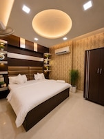 Quarto moderno com cama grande, estantes embutidas, ar condicionado e luminária decorativa no teto.