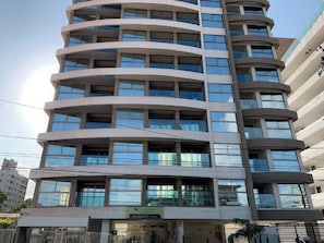 A multi-story building with a curved facade, large windows, and a visible storefront at the ground level. - New Listing (Natal)