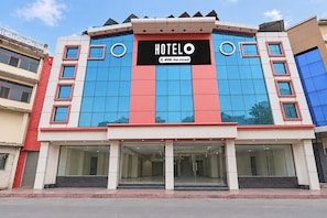 Un hôtel reconnaissable à son grand panneau « HÔTEL  », doté d’une façade moderne avec de grandes fenêtres et d’un toit plat.