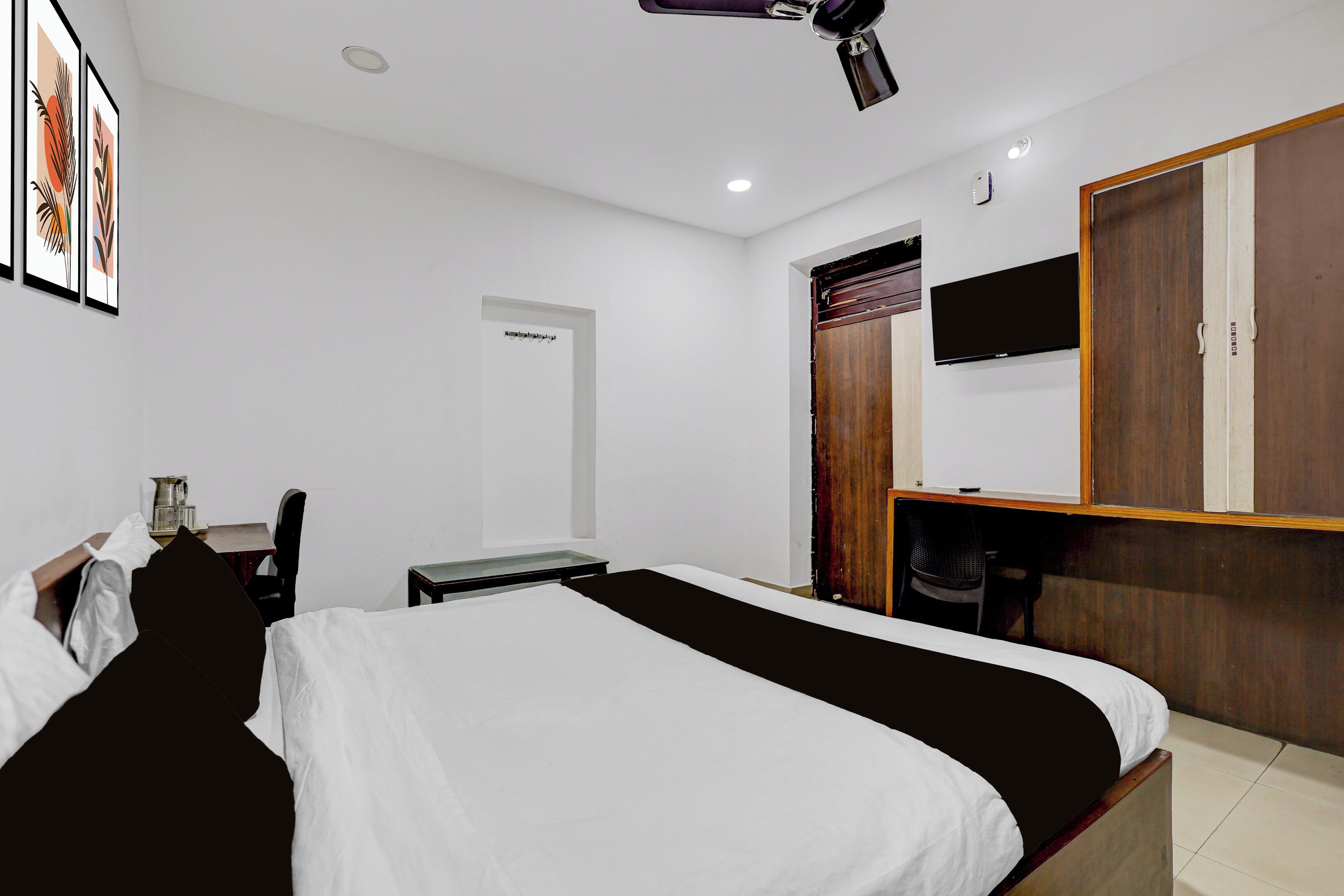 Un dormitorio con cama, escritorio, silla, armario y televisor.