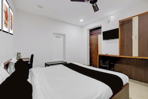 Un dormitorio con cama, escritorio, silla, armario y televisor.