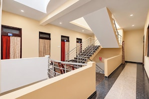 Un couloir d’hôtel avec un escalier, des portes numérotées 201 et 204, et un panneau d’indication concernant la sécurité incendie.