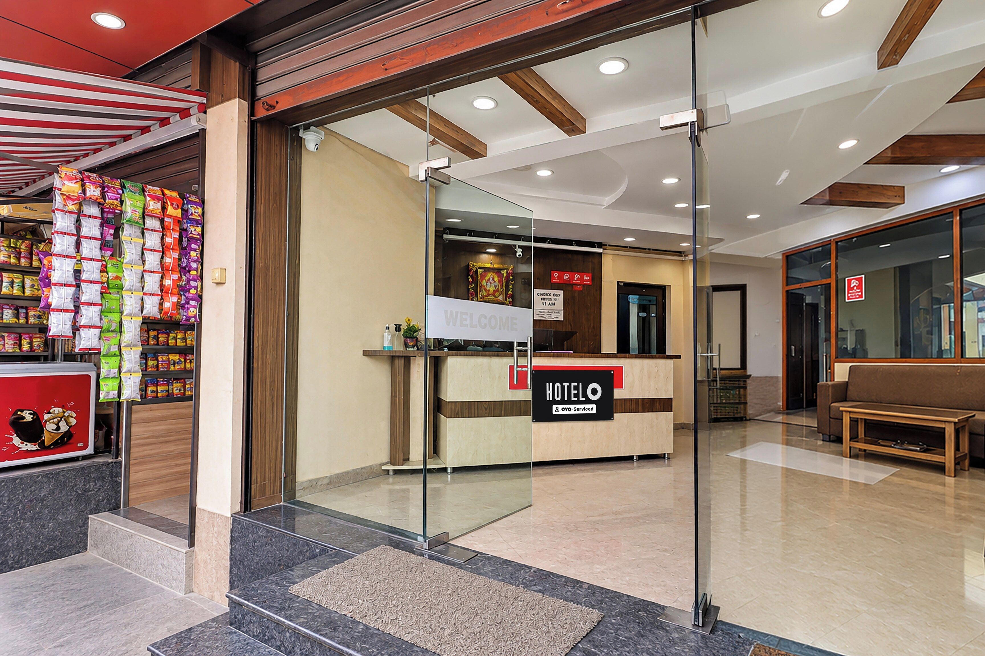 Zona de recepción de un hotel, con mostrador de recepción, un cartel con la palabra 'Welcome' y un cartel con la palabra 'HOTELO'.