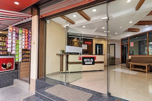 Zona de recepción de un hotel, con mostrador de recepción, un cartel con la palabra 'Welcome' y un cartel con la palabra 'HOTELO'.