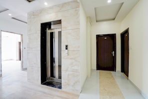 Un interior moderno con una pared de mármol, un ascensor y un pasillo que conduce a una puerta con el número 303.
