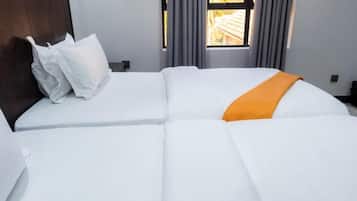A neatly made bed with white bedding and an orange throw blanket.