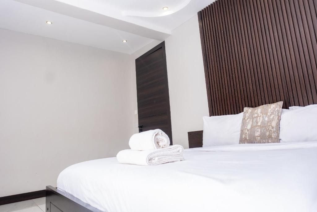 Una habitación de hotel moderna con una cama bien hecha, un cabecero de madera y una pared decorativa oscura.