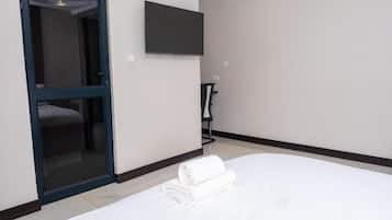 Habitación de hotel con cama, televisor montado en la pared y puerta que da a un baño.
