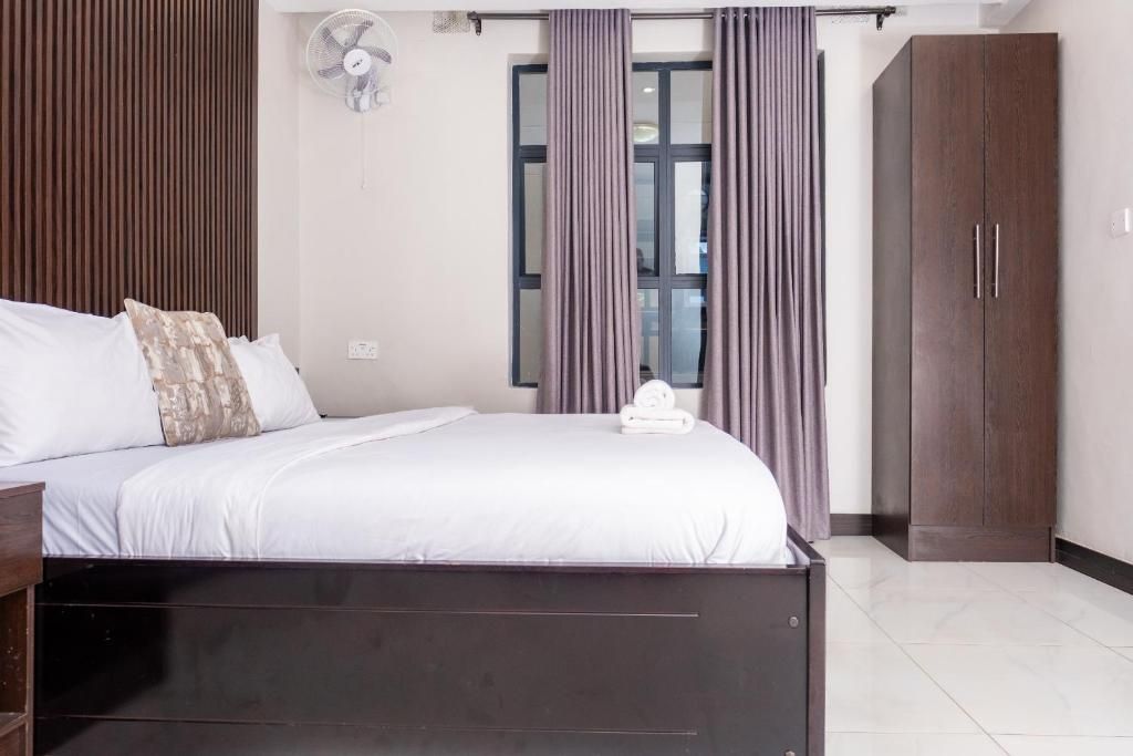 Un dormitorio con cama, armario, ventilador y ventana con cortinas.
