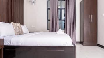 Un dormitorio con cama, armario, ventilador y ventana con cortinas.