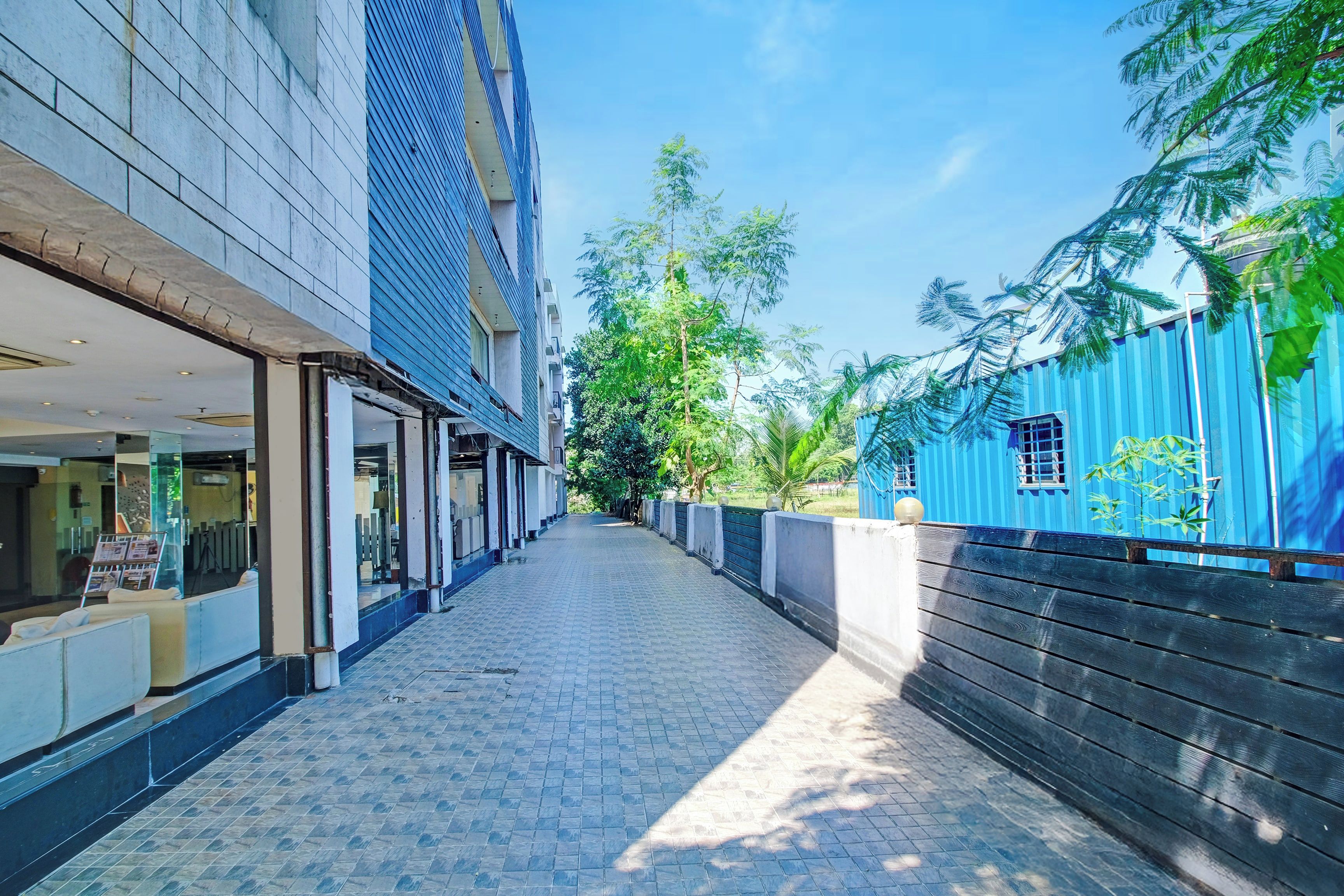 A narrow paved walkway flanked by buildings, one with a blue facade and the other with a white facade.