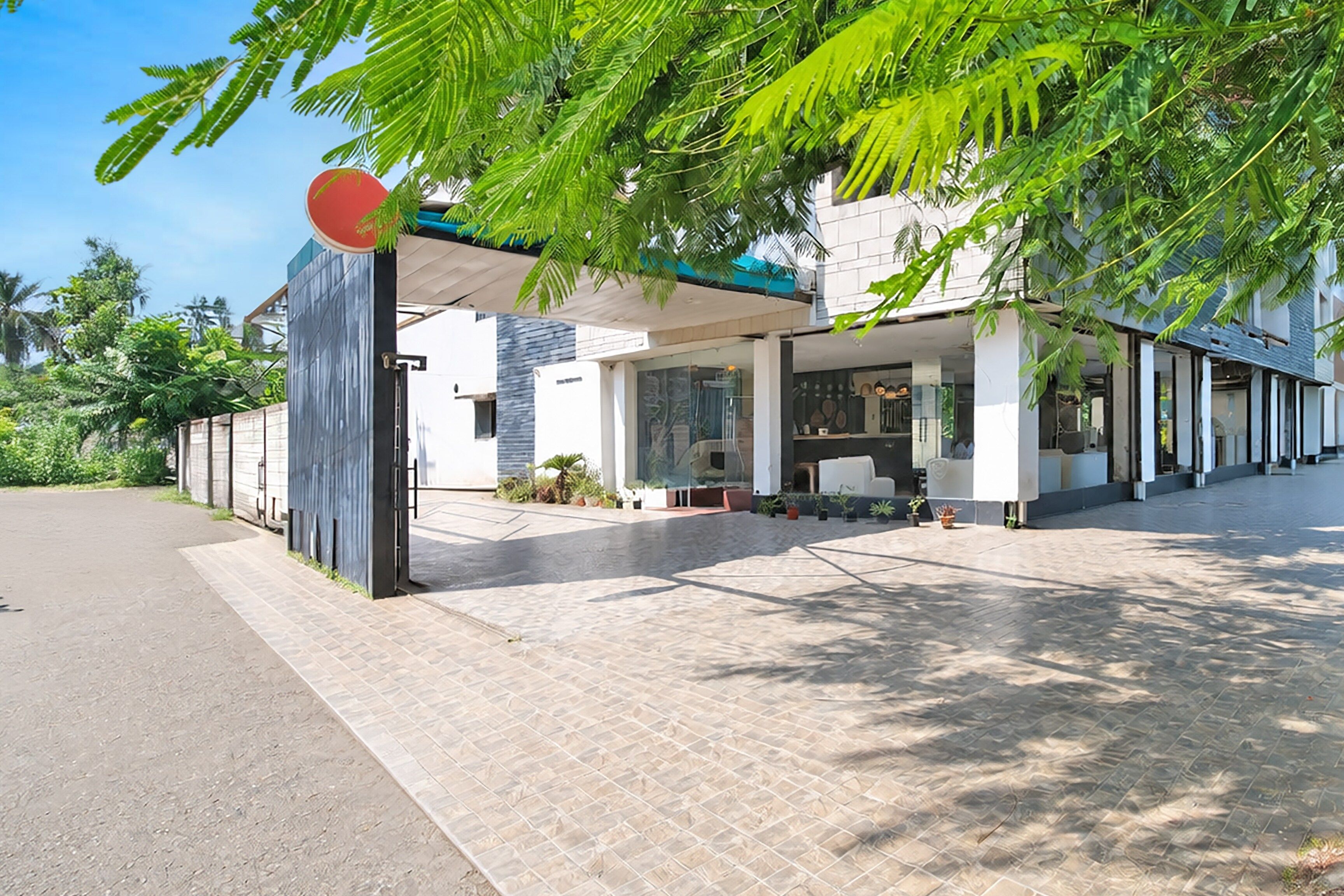A modern building with a covered entrance, a clear sky, and a paved driveway.