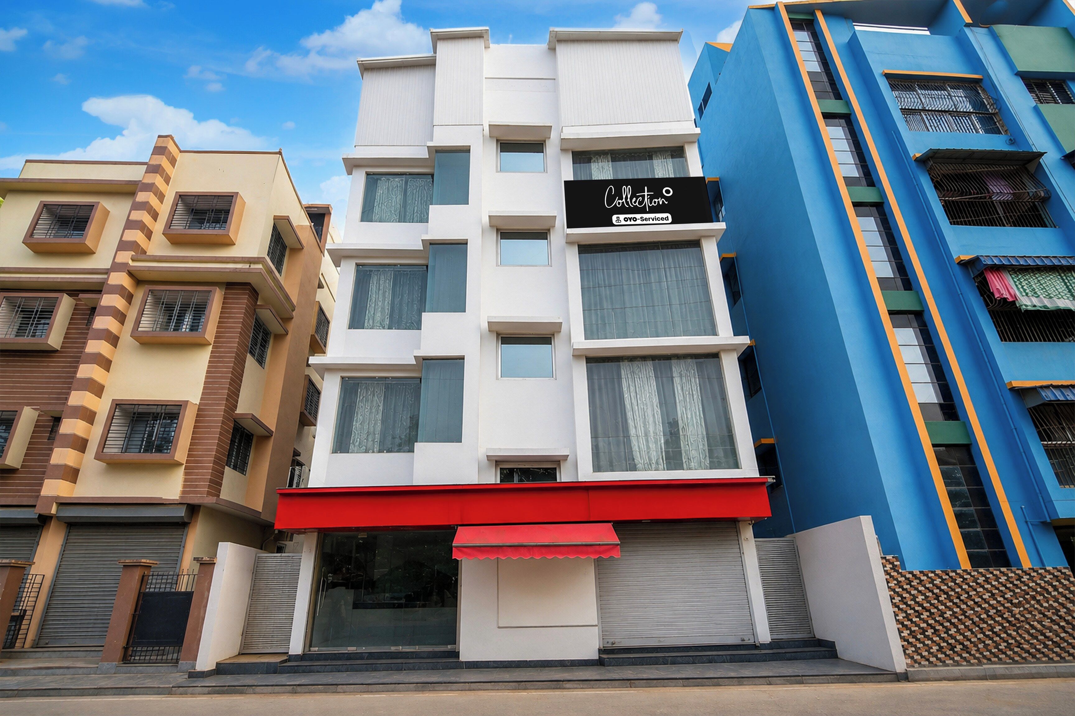 A multi-story building with a red awning, a sign indicating a service, and a blue facade.