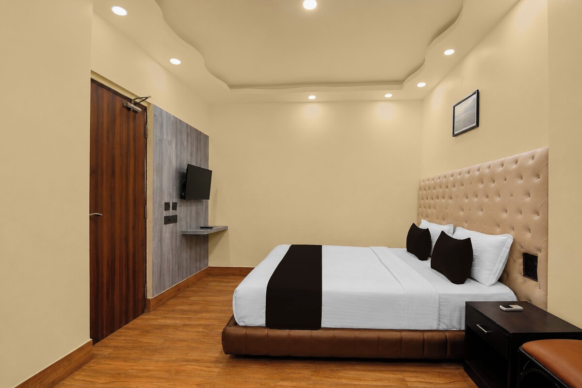A hotel room with a bed, a bedside table, a TV, and a wardrobe.