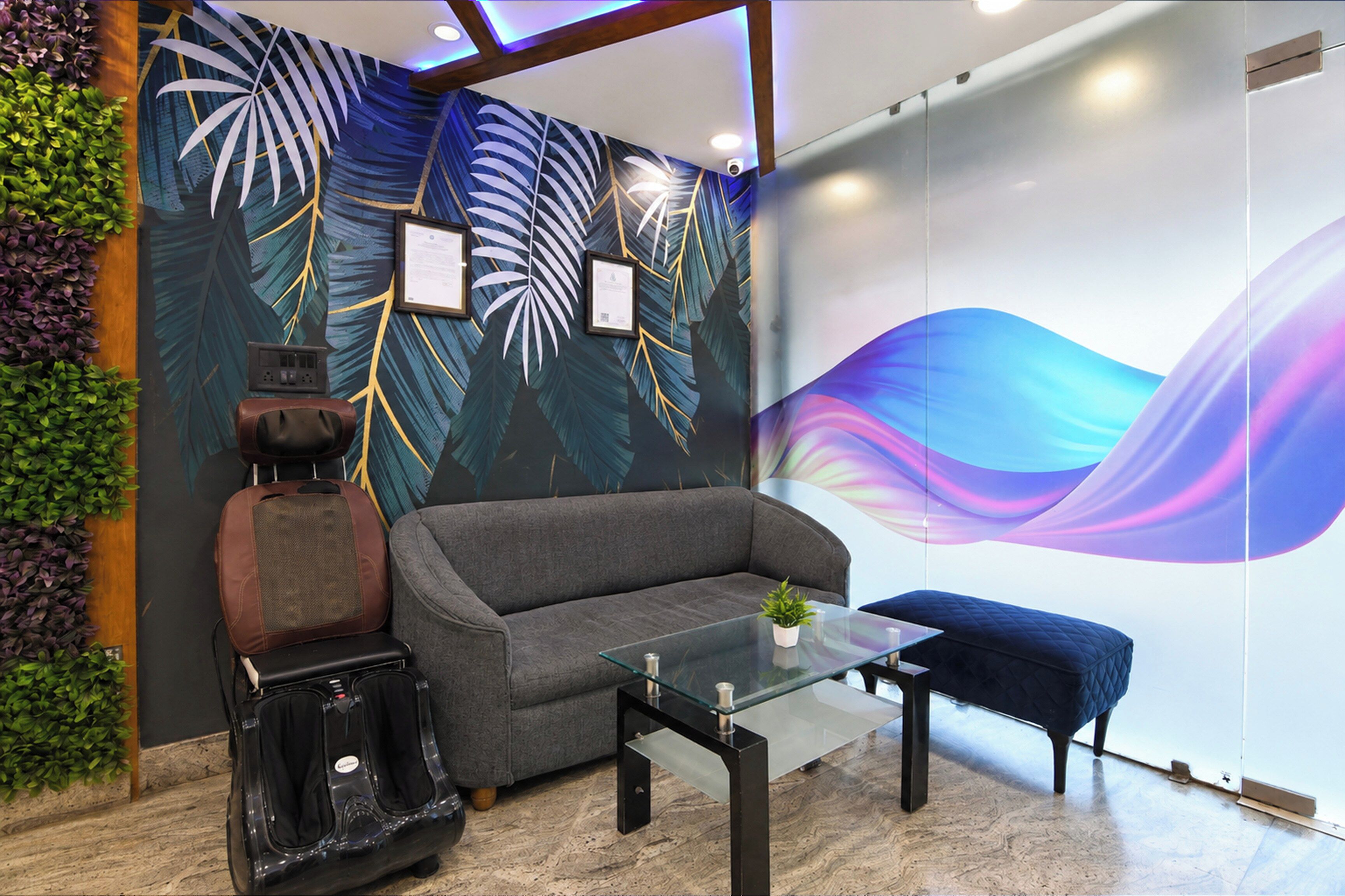 Ein modernes Interieur mit einer Couch, einem Glastisch und einer Wand mit tropischem Blattmuster.