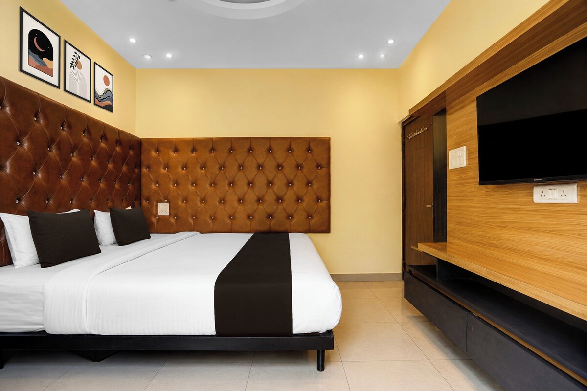 Un dormitorio moderno con una tapicería capitonada en la cabecera, una cama grande, un televisor de pantalla plana y obras de arte en la pared.