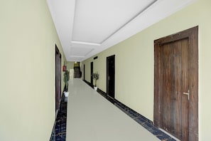 A hallway with a marble floor, a wooden door, and a potted plant. - Hotel O Kashi Ghat Varanasi (Varanasi)