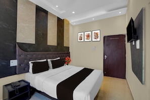 Ein Hotelzimmer mit einem großen Bett, einem Flachbildfernseher und einer Tür.